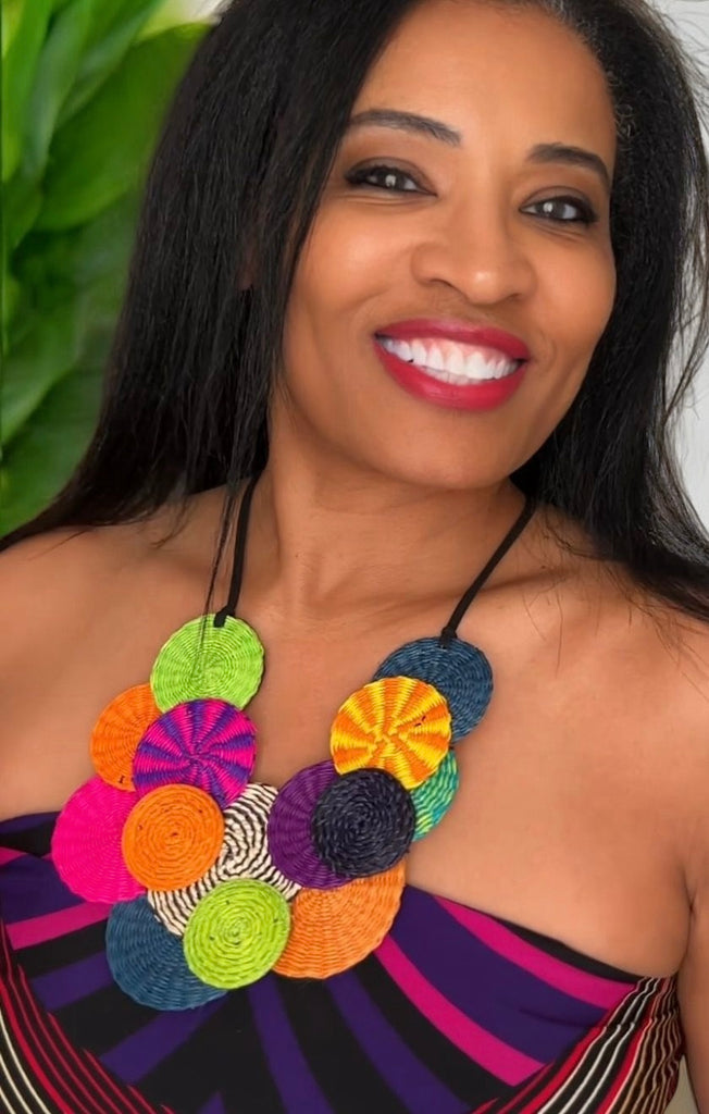 A woman wearing a colorful geometric patterned necklace with a variety of shapes and colors.